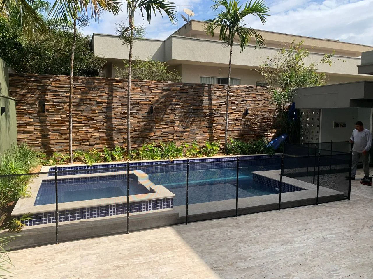 Cerca removível preta ao redor de piscina residencial, integrada ao jardim e à área de lazer